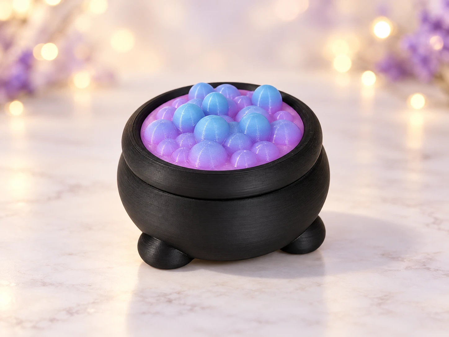 Black cauldron sandbox with a blue and purple rainbow bubble top against a softly lit background.
